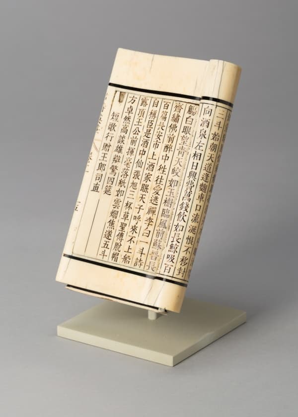 A work made of ivory, text carved and inked.